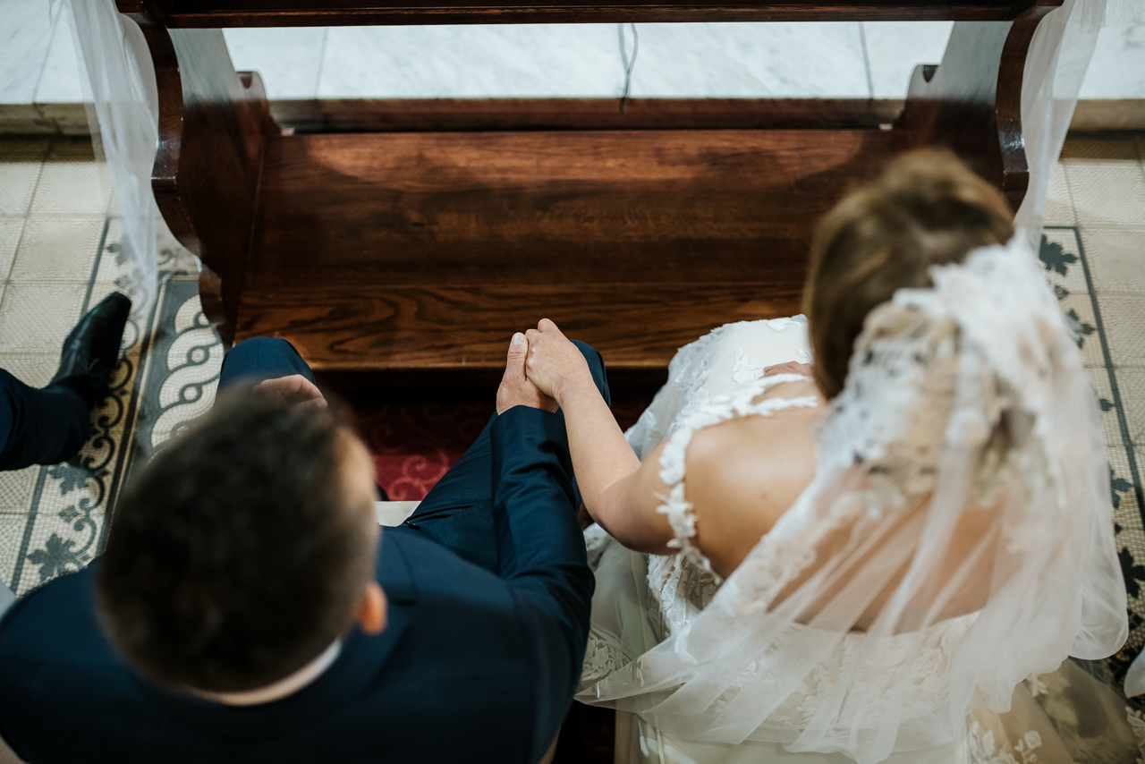the detail of bride and groom holding each other hand in church ceremony